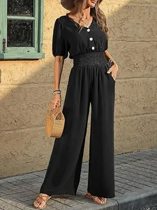 Close-up of black short-sleeved wide-leg jumpsuit with smocked waist and button detail