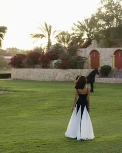 Rückenansicht einer Frau in einem schwarz-weißen Maxikleid auf einer grünen Wiese