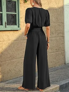 Back view of elegant black short sleeve jumpsuit with smocked waist and wide legs