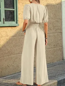 Back view of elegant beige short sleeve jumpsuit with smocked waist and wide legs