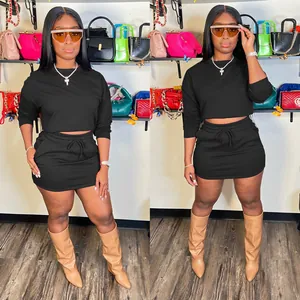 Trendy chic black two-piece set featuring long sleeve crop top and drawstring mini skirt.