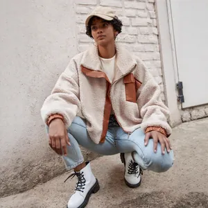 Detailed shot of beige sherpa fleece jacket with brown leather contrast patches