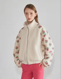 Detaillierte Ansicht der weißen Fleecejacke mit Blumenmuster an den Ärmeln und Reißverschluss.