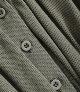 Detailopname van de olijfgroene ribgebreide stof met een ontwerp met knoopsluiting