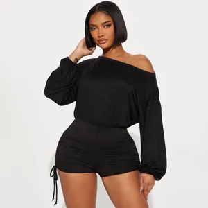 Detail view of a black off-the-shoulder long-sleeved romper with ruched sides