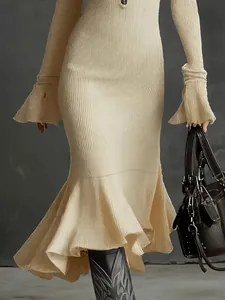 Gros plan d'une robe sirène beige en maille avec manches cloche et ourlet à volants