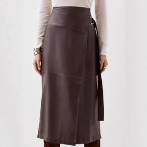 Close-up of elegant brown PU leather skirt featuring a chic irregular slit and waist belt detail