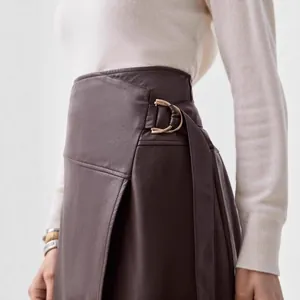 Detail of elegant brown PU leather skirt with adjustable belt and metal buckle.