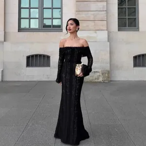 Elegant Asian woman in a black lace off-the-shoulder evening gown with long flared sleeves.