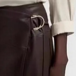 Detail view of the adjustable silver metal D-ring buckle on a brown PU leather skirt