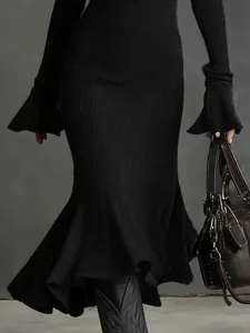 Gros plan d'une élégante robe sirène côtelée noire avec des manches évasées et un ourlet fluide.
