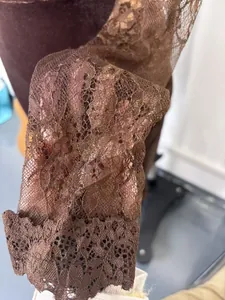 Close-up detail of elegant brown floral lace sleeve on a see-through dress