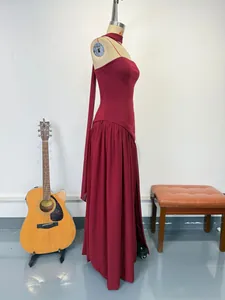 Side view of elegant burgundy backless gown with halter streamers and leg slit