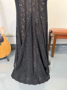 Close-up macro view of the delicate black floral lace texture on an elegant evening gown hem
