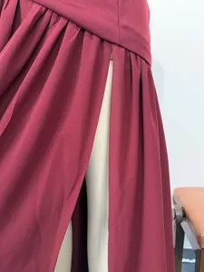 Close-up detail showing the high slit and pleated waist on a burgundy evening gown.