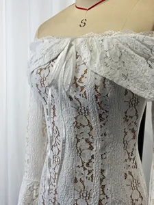 Close-up detail of white lace hollow-out fabric on off-the-shoulder flared sleeve dress.