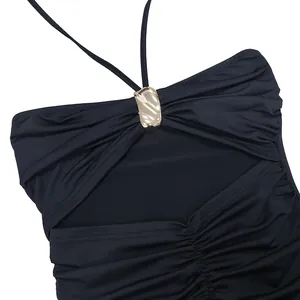 Gros plan de la boucle dorée décorative et du détail ajouré froncé sur la robe noire.