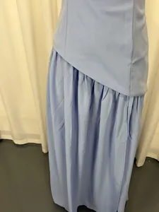 Detail shot of the waist pleats and asymmetrical hem of a light blue evening dress