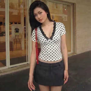 Modella indossa una maglietta a pois sexy con scollo a V in pizzo e vestibilità slim