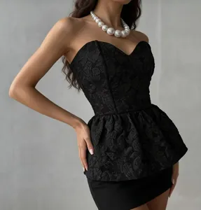 Close-up van zwarte jacquard peplum top met hartvormige halslijn en getextureerde stof.