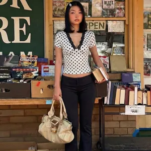 Maglia vintage a pois con scollo a V e bordo in pizzo in una libreria accogliente