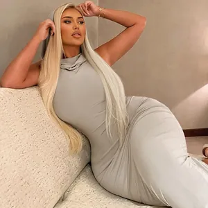 Elegant blonde model wearing a grey sleeveless hooded maxi dress on a sofa