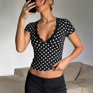 Dettaglio di un top sexy a pois neri con scollo a V e rifiniture in pizzo elegante.