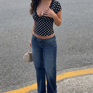 Dettaglio di un top nero a pois da donna con scollo a V, pizzo e vestibilità slim.