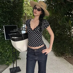 Vista dettagliata di una maglietta a pois slim fit con scollo a V e pizzo su modella