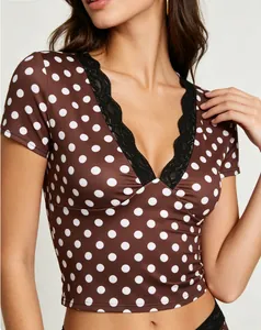 Dettaglio del crop top con scollo a V, motivo a pois marroni e bordo in pizzo nero.