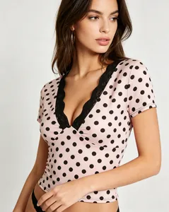 Dettaglio del top rosa a pois da donna con bordo in pizzo nero sullo scollo a V