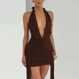 Detailed view of brown halter dress featuring deep V-neck, rucking, and droplet accents