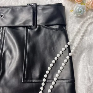 Detailed view of sexy black PU leather mini skirt with Y2K waist grommets
