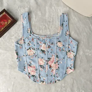 Top a corsetto azzurro con stampa floreale e dettagli steccati su sfondo di peluche