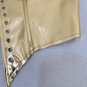 Gros plan détaillé d'un corset métallique doré avec des oeillets argentés et des coutures fines
