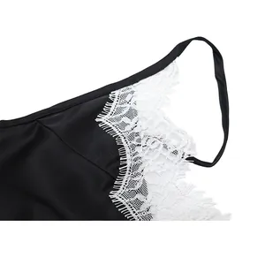 Detailed view of the delicate white floral lace trim on a sexy black satin camisole top