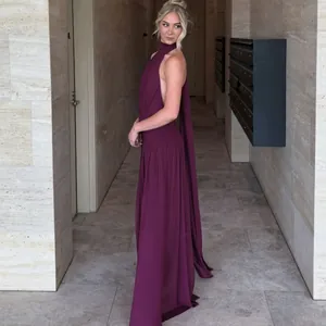 Elegant plum halter neck backless maxi dress with trailing detail in a hallway