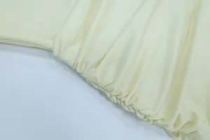 Dettaglio ravvicinato delle delicate increspature e della trama liscia di un abito crema