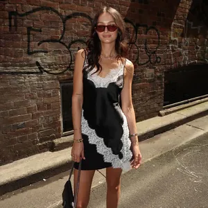 Black satin camisole with white lace trim worn by a model in a street style setting.