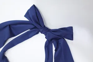 Detailed view of an elegant navy blue bow on a sophisticated halter neck evening dress.