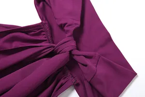 Detail shot of the back tie knot on a purple halter maxi dress with fine stitching.