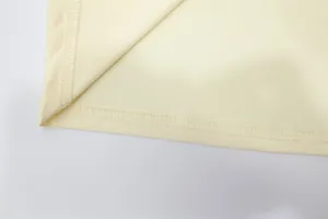 Detailed close-up showing the high-quality overlock stitching on a cream fabric dress