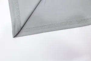 Detailed close-up of neat stitching on the hem of a light grey elegant dress fabric.