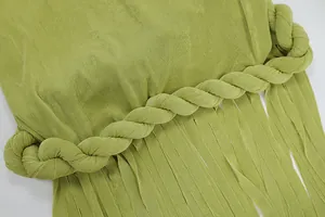 Dettaglio ravvicinato di un abito verde lime con corda intrecciata e lunghe frange