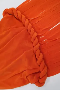 Dettaglio dell'abito arancione con scollo all'americana, corda intrecciata e frange.