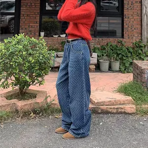 Vue détaillée d'un jean bleu large à pois tendance porté avec un pull rouge confortable