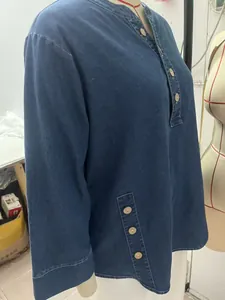 Detail of the side seams and decorative wooden buttons on a washed blue denim tunic top