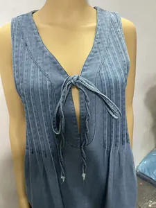 Detail of sleeveless pleated washed denim jumpsuit with tie-front neckline