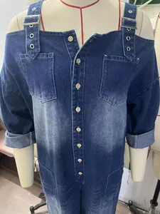 Detail of off-shoulder denim jumpsuit with adjustable metal buckle straps and button front.