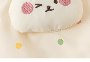 Macro detail of cute character embroidery and polka dots on girl's outdoor jacket fabric